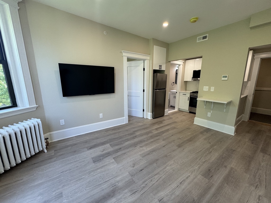 41 Edgerly Road, Unit 28 Boston, MA 02115 - Photo 4 of 13 a view of a livingroom with wooden floor and a flat screen tv