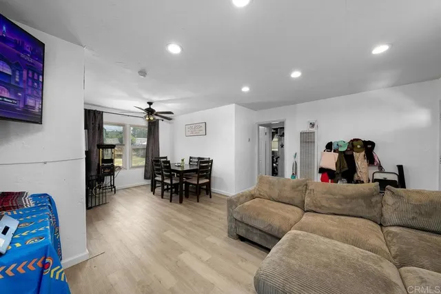 a living room with furniture and a dining table with bookshelf