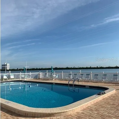 a view of swimming pool with a table and chairs in ocean