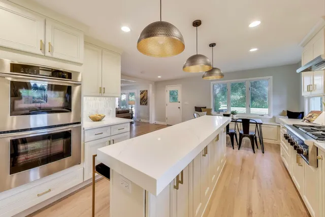 a kitchen with stainless steel appliances a stove a sink a microwave a center island and furniture