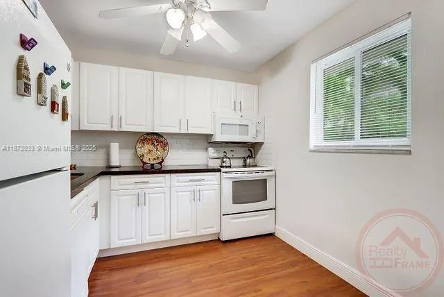 a kitchen with granite countertop white cabinets and white appliances
