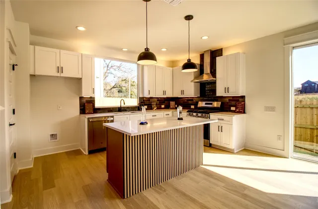 a kitchen with stainless steel appliances granite countertop a sink a stove a refrigerator and white cabinets
