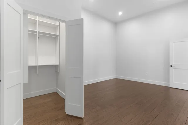 an empty room with wooden floor & cabinet and window