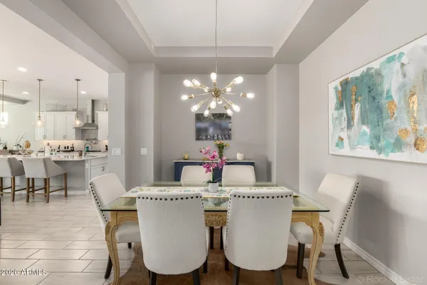 a dining room with wooden floor a chandelier a wooden table and chairs