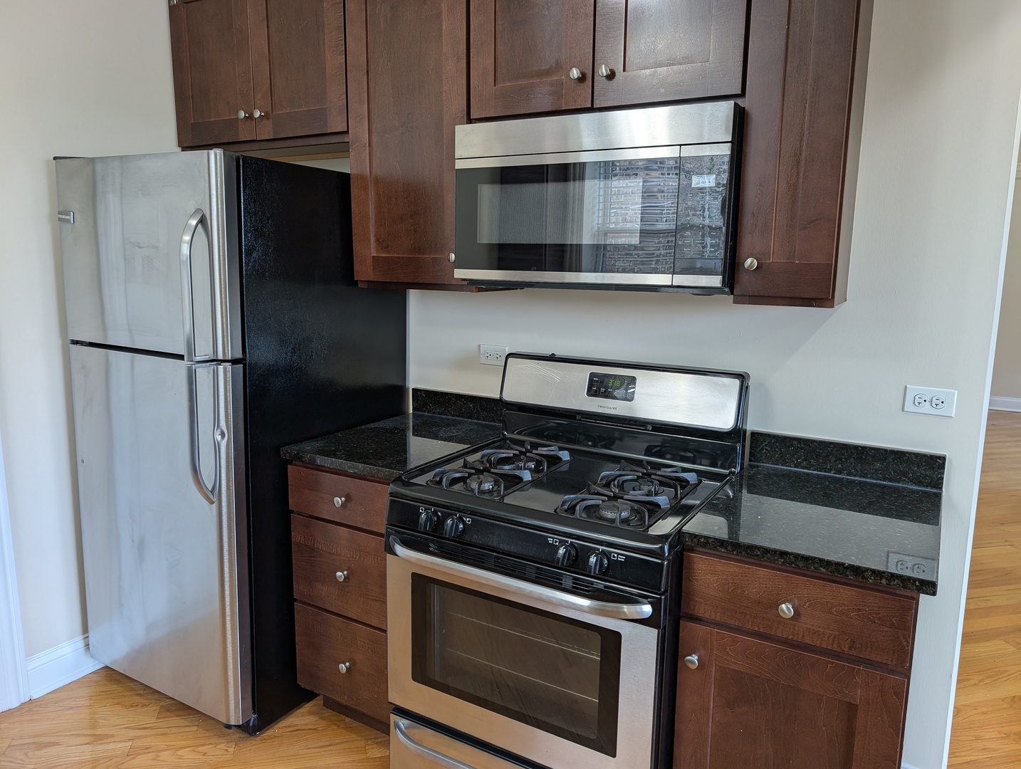 4014 North Central Park Avenue, Unit 3E Chicago, IL 60618 - Photo 4 of 11 a kitchen with stainless steel appliances wooden cabinets and a stove top oven