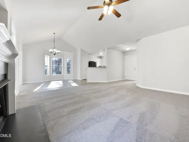 a view of a livingroom with a chandelier fan and kitchen view
