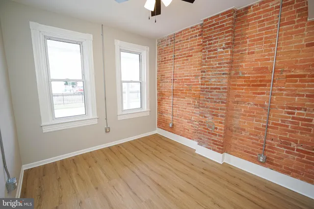 an empty room with wooden floor and a ceiling fan