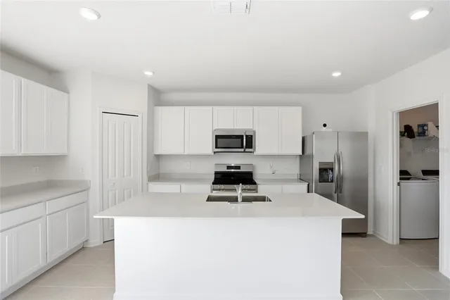 a kitchen with a refrigerator a stove top oven a sink and cabinets