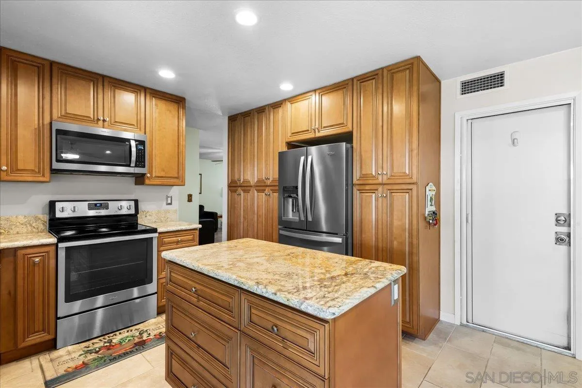 10738 2nd Street Santee, CA 92071 - Photo 11 of 52 a kitchen with granite countertop wooden cabinets a stove and stainless steel appliances