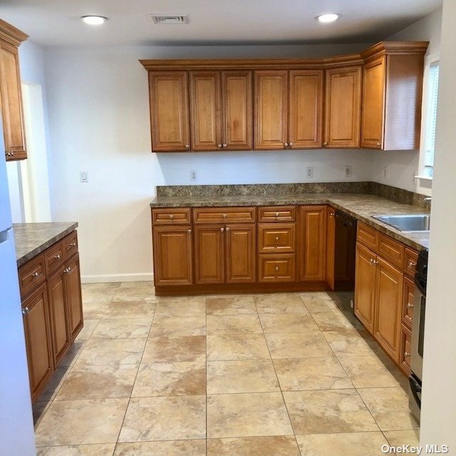 a kitchen with granite countertop a sink a stove top oven cabinets and a window