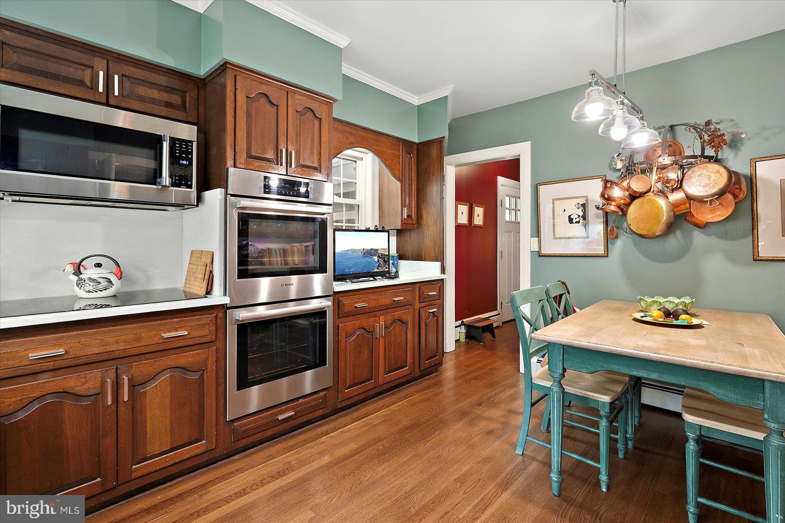 921 Riverside Drive Salisbury, MD 21801 - Photo 21 of 62 a kitchen with granite countertop a stove a microwave a dining table and chairs with wooden floor
