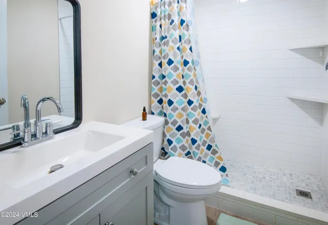 a bathroom with a sink a toilet and shower curtain