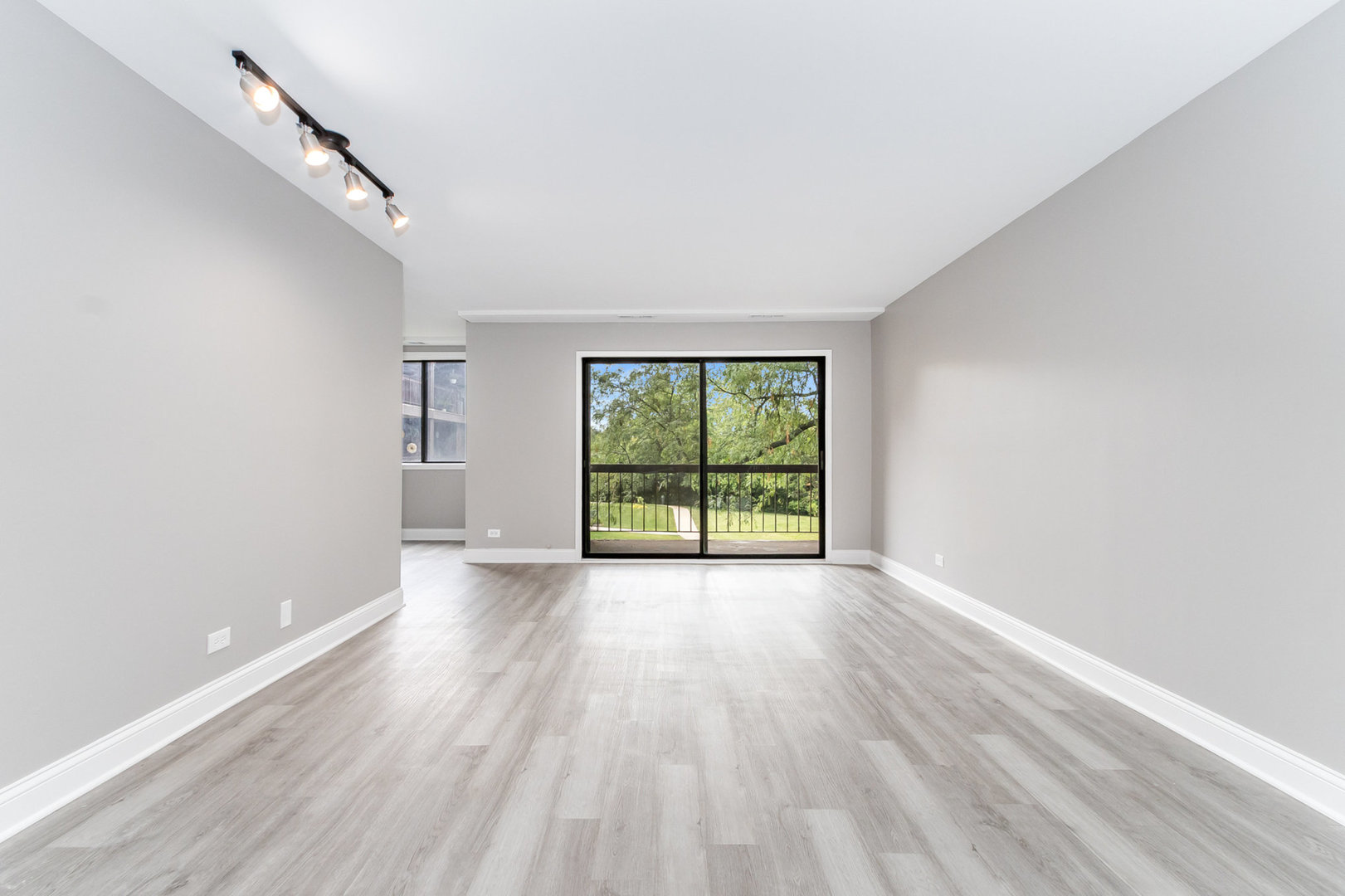 470 Raintree Court, Unit 2H Glen Ellyn, IL 60137 - Photo 6 of 22 a view of an empty room with wooden floor and a window