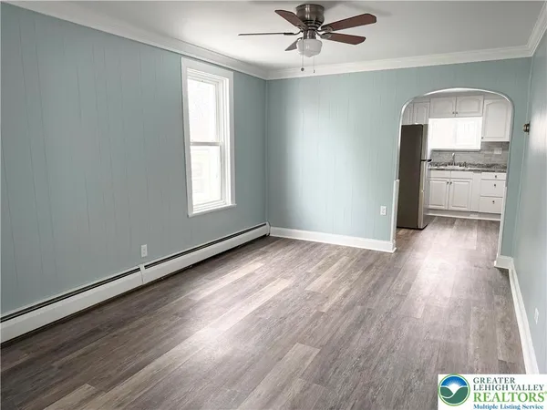 an empty room with wooden floor a ceiling fan and windows