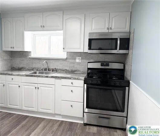 a kitchen with granite countertop white cabinets and stainless steel appliances