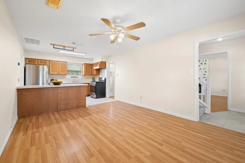 a view of a kitchen with wooden floor and a ceiling fan