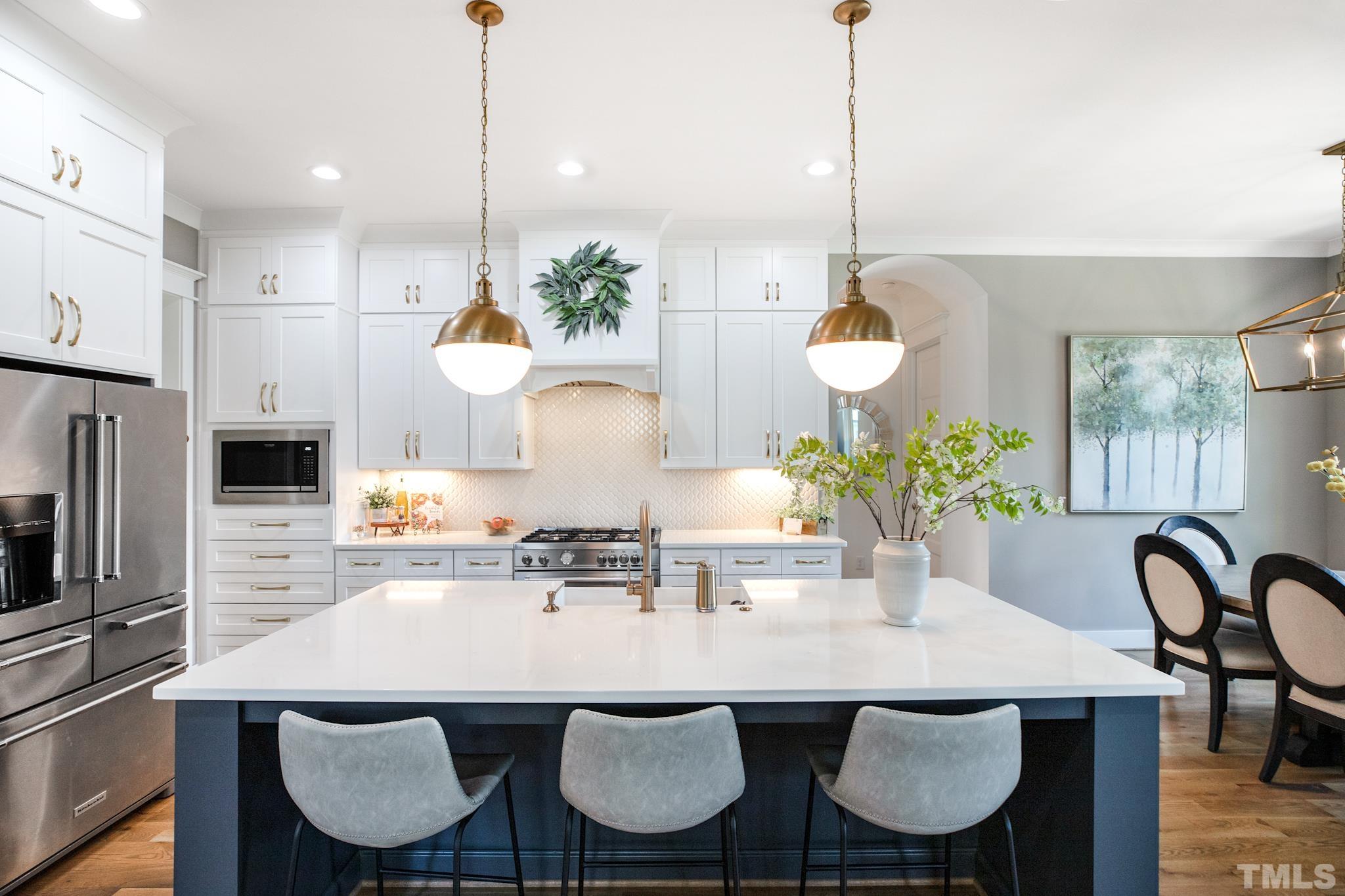 1420 Margrave Drive Wake Forest, NC 27587 - Photo 15 of 30 a kitchen with kitchen island a dining table chairs and white cabinets