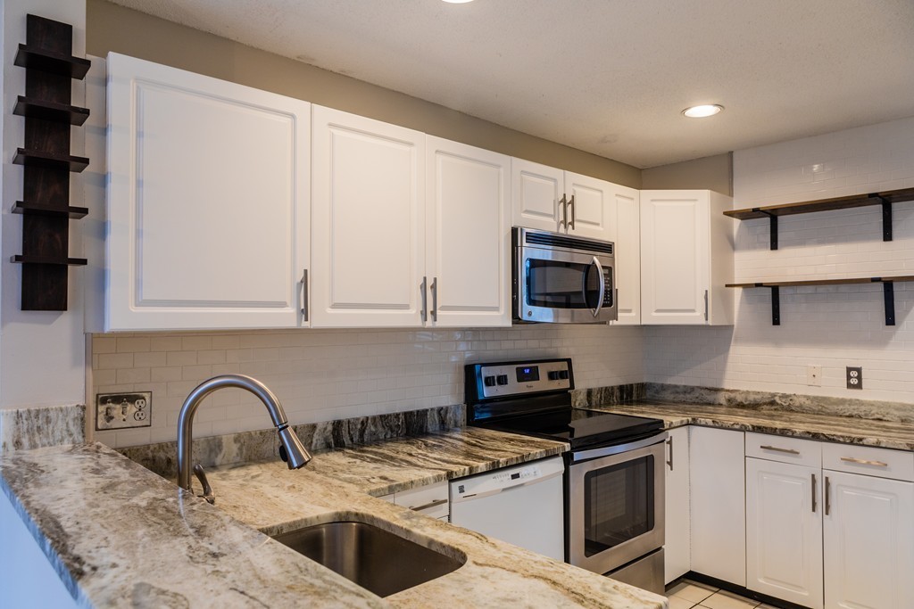 85 Bishops Forest Drive, Unit 85 Waltham, MA 02452 - Photo 3 of 32 a kitchen with granite countertop a sink and a stove top oven with wooden floor