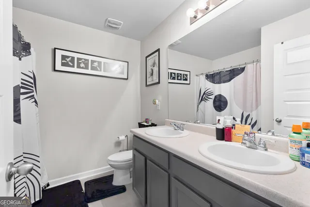 a bathroom with a double vanity sink mirror and toilet
