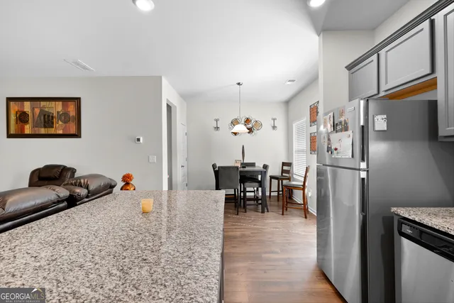 a kitchen with stainless steel appliances granite countertop a refrigerator and a dining table