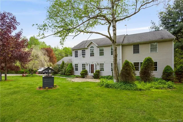 a front view of a house with a garden and trees