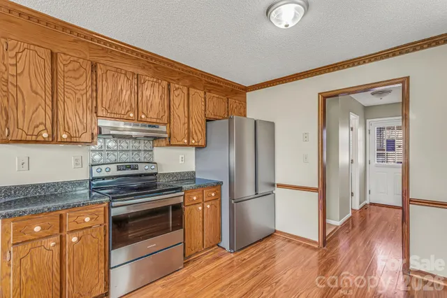 a kitchen with stainless steel appliances granite countertop wooden cabinets a refrigerator and a sink