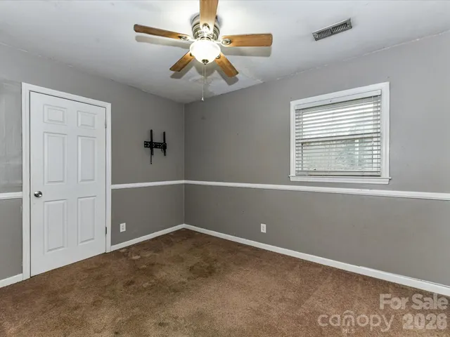 an empty room with a window and a fan