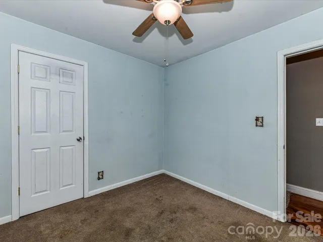 a view of an empty room and chandelier fan