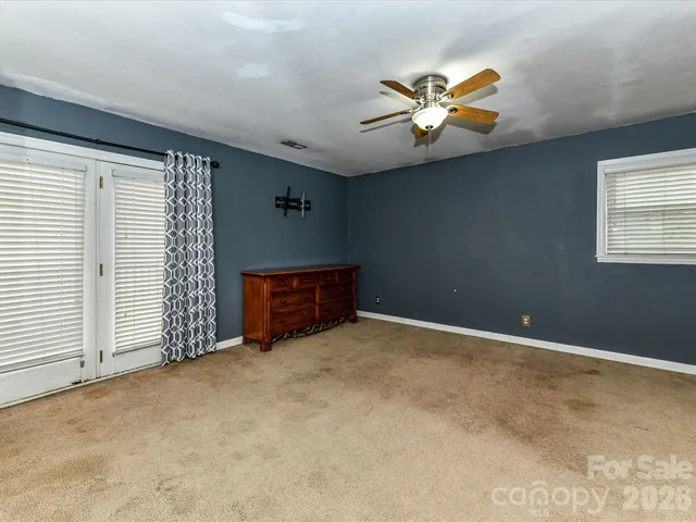 an empty room with closet and a chandelier fan