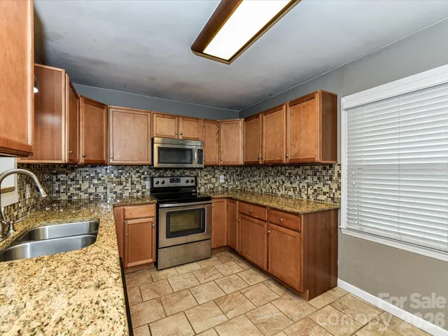 a kitchen with stainless steel appliances granite countertop a sink stove and cabinets