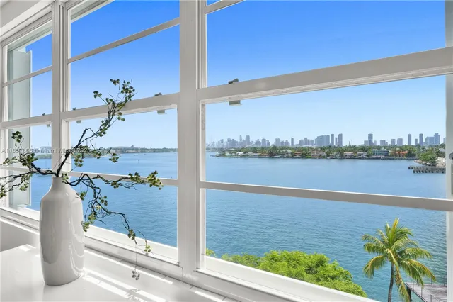 a view of a lake with a floor to ceiling window and palm tree