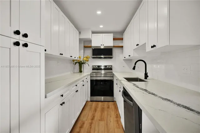 a kitchen with granite countertop white cabinets and stainless steel appliances