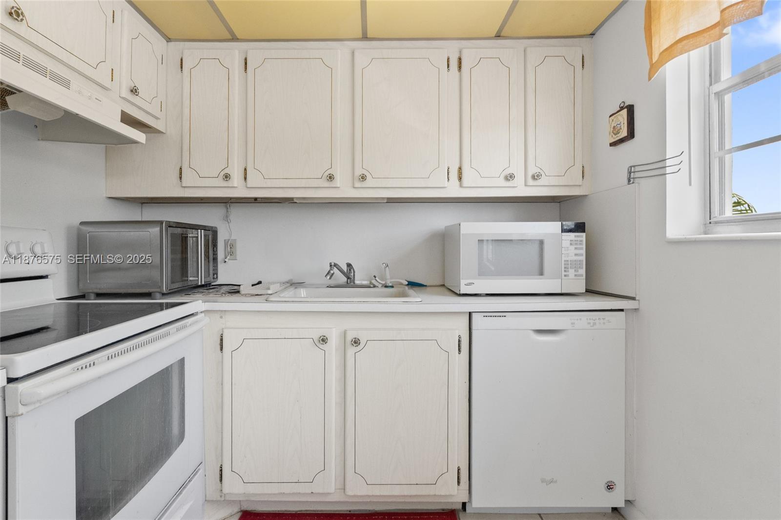 431 Markham South, Unit 431 Deerfield Beach, FL 33442 - Photo 26 of 30 a kitchen with white cabinets and white appliances