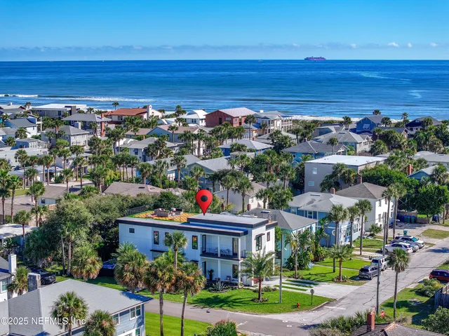 a palm tree sitting in front of a house with a garden