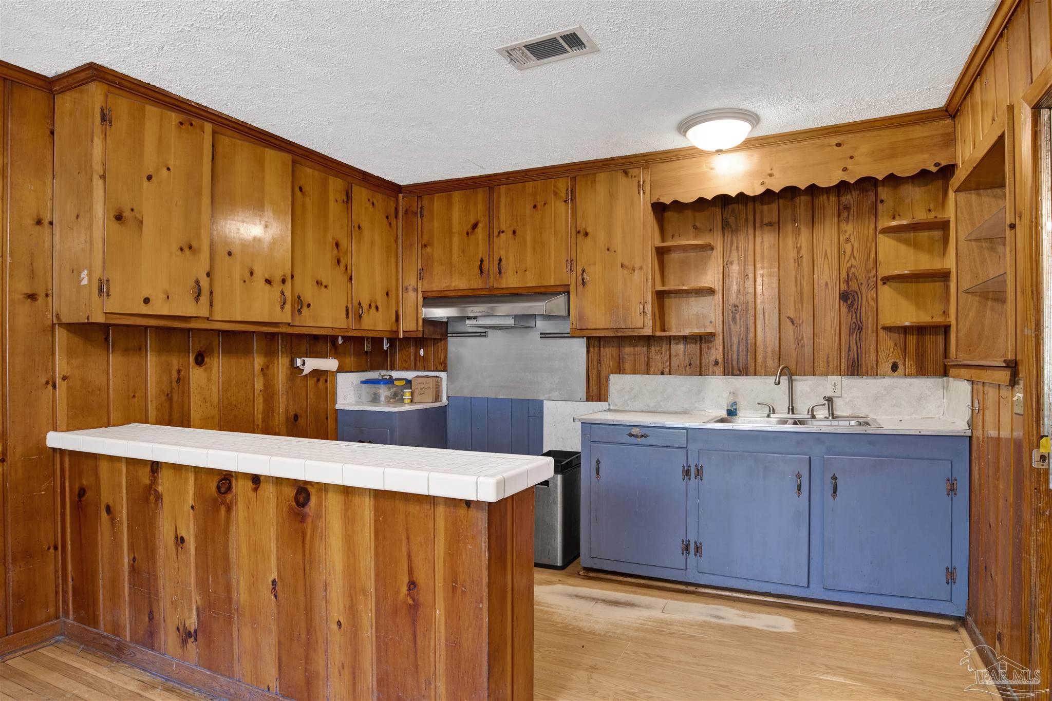 533 Ditmar Street Pensacola, FL 32503 - Photo 11 of 37 a kitchen with sink cabinets and wooden floor