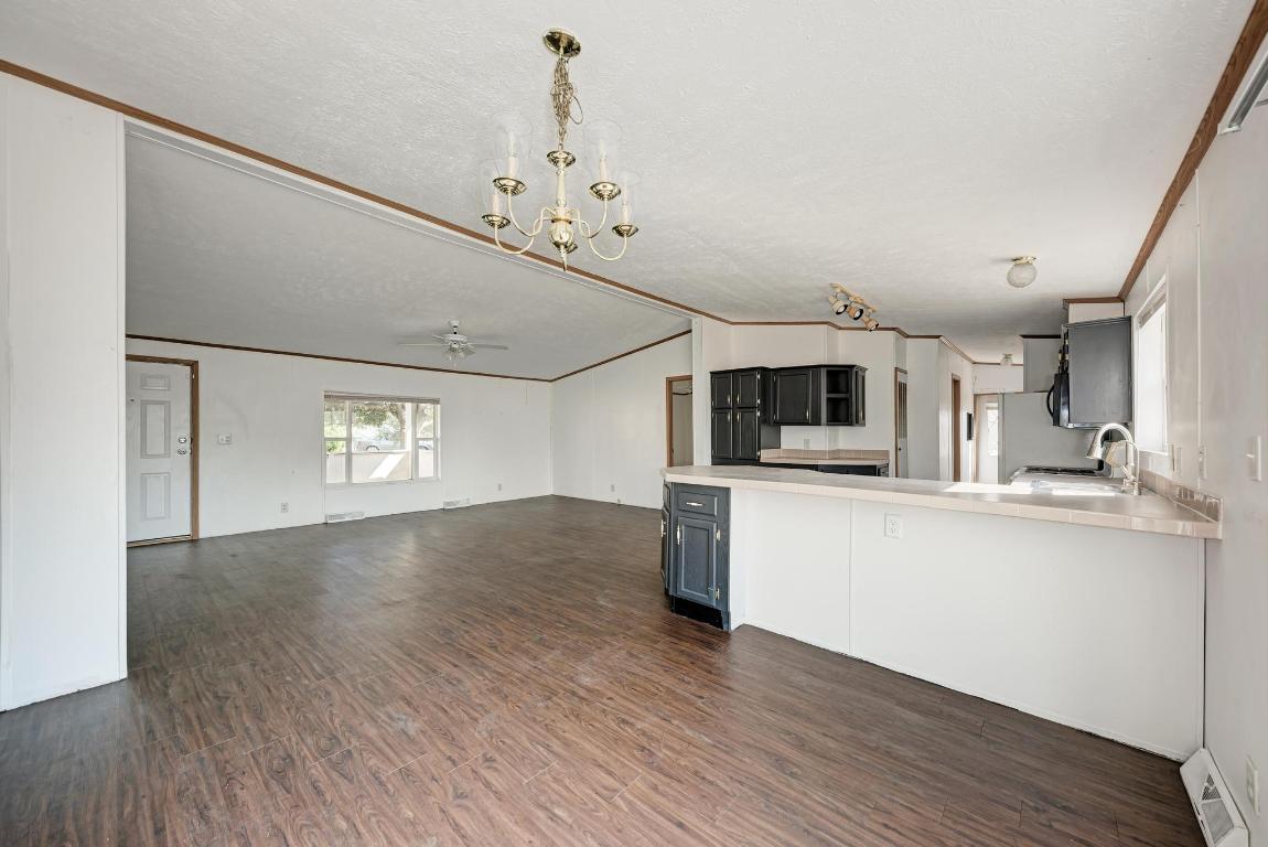 187 Horseshoe Bend Road San Marcos, TX 78666 - Photo 11 of 38 Kitchen featuring dark wood-style floors, light countertops, hanging light fixtures, ornamental molding, and vaulted ceiling