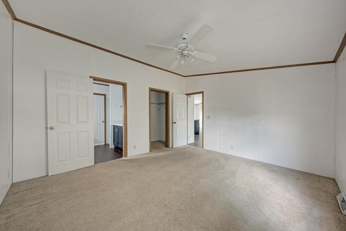 187 Horseshoe Bend Road San Marcos, TX 78666 - Photo 18 of 38 Unfurnished bedroom with ensuite bathroom, ornamental molding, carpet flooring, a spacious closet, and ceiling fan