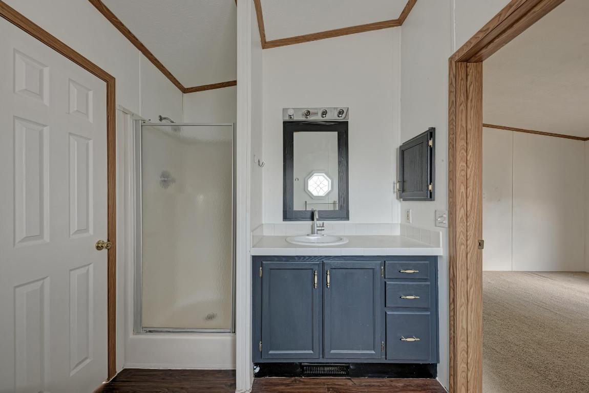 187 Horseshoe Bend Road San Marcos, TX 78666 - Photo 19 of 38 Bathroom featuring crown molding, a shower stall, vanity, and dark wood-style flooring