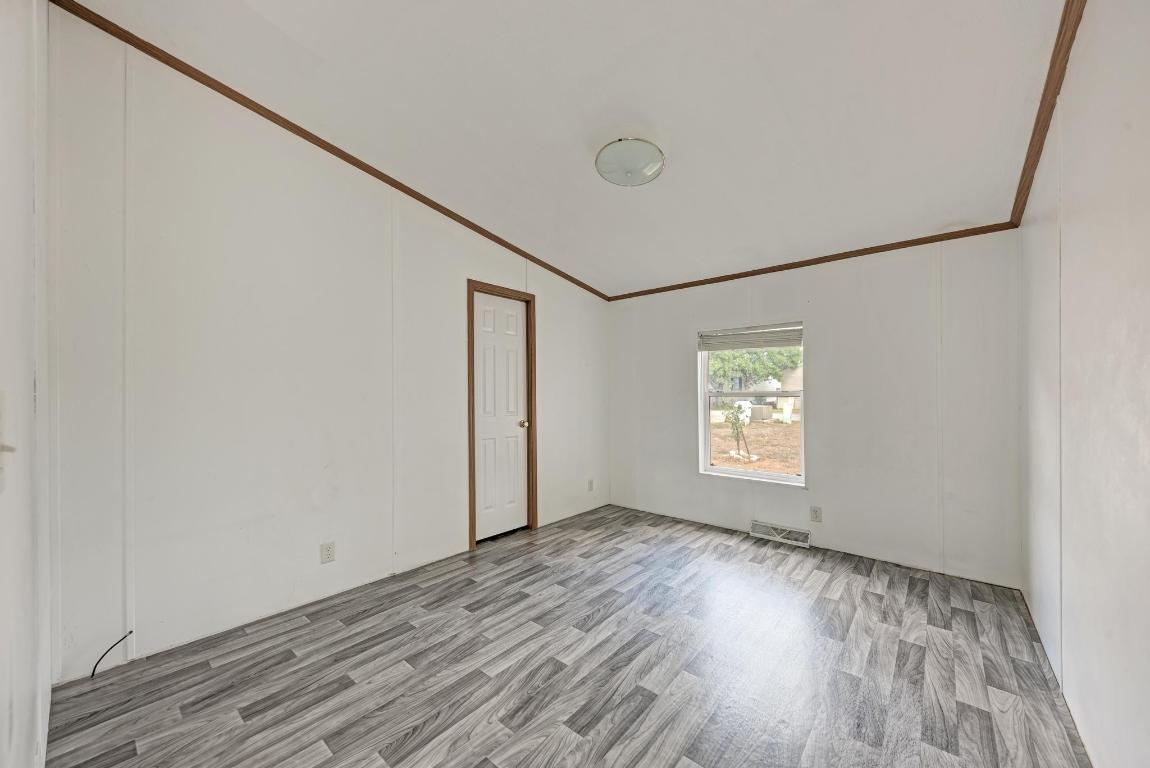 187 Horseshoe Bend Road San Marcos, TX 78666 - Photo 22 of 38 Empty room featuring crown molding, light wood-style flooring, and lofted ceiling