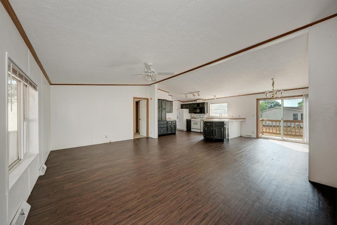 187 Horseshoe Bend Road San Marcos, TX 78666 - Photo 6 of 38 Unfurnished living room with crown molding, dark wood finished floors, a chandelier, a baseboard heating unit, and vaulted ceiling