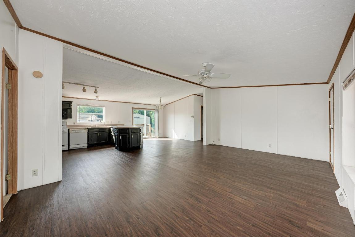 187 Horseshoe Bend Road San Marcos, TX 78666 - Photo 7 of 38 Unfurnished living room featuring dark wood finished floors, a textured ceiling, a chandelier, a ceiling fan, and crown molding