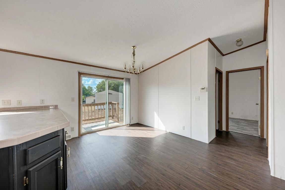 187 Horseshoe Bend Road San Marcos, TX 78666 - Photo 10 of 38 Unfurnished dining area with ornamental molding, dark wood-type flooring, and a chandelier