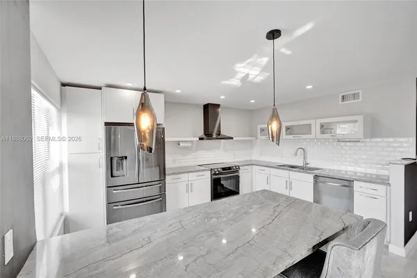 a large kitchen with cabinets table chairs sink and refrigerator