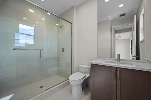 a bathroom with a granite countertop sink a toilet and shower