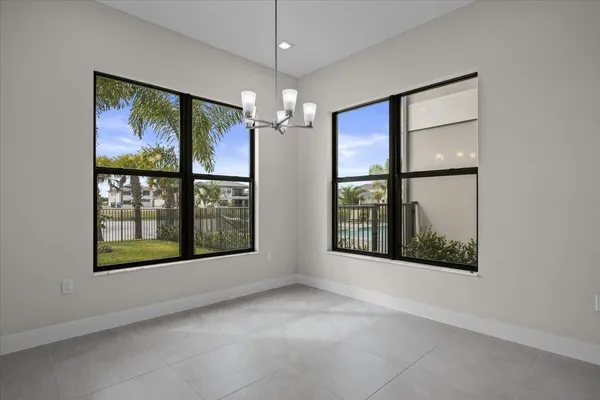 a view of an empty room with windows and chandelier fan