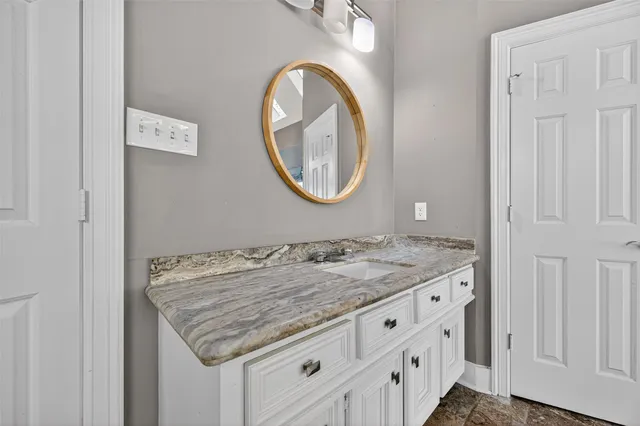 a bathroom with a granite countertop sink and a mirror