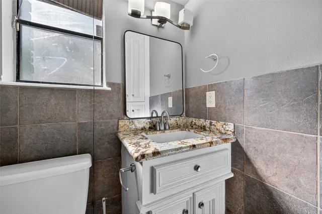 a bathroom with a granite countertop sink a toilet and a mirror