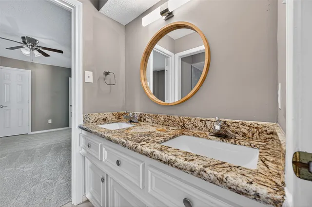 a bathroom with a granite countertop sink and a mirror