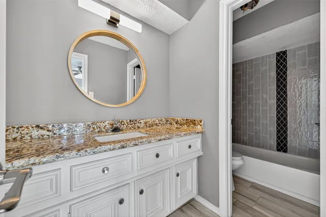 a bathroom with a granite countertop sink and a mirror