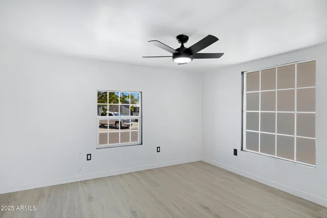an empty room with wooden floor cabinet and windows